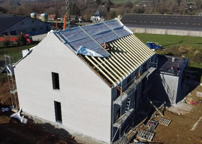 Vue aérienne d'une nouvelle construction avec des ouvriers travaillant sur la toiture en bois d'une maison blanche