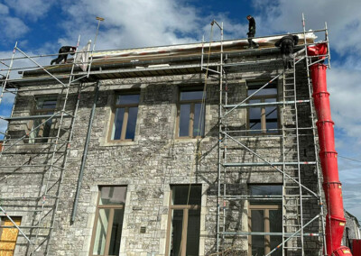 Des ouvriers qui travaillent sur la toiture d'une maison en pierres grises