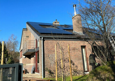 Toiture d'une maison en brique équipée de panneaux solaires, avec cheminée