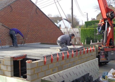 Des ouvriers qui placent des dalles en béton sur un chantier de construction d'une annexe de maison