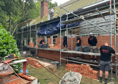 Equipe de François R. qui travaille à la façade d'une maison en briques rouges