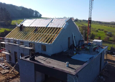 Des ouvriers qui réalisent la toiture d'une maison neuve en cours de construction