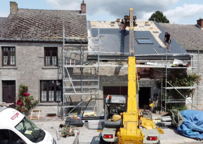 Chantier de rénovation d'une maison en pierre avec des ouvriers qui s'occupent de l'isolation de la toiture